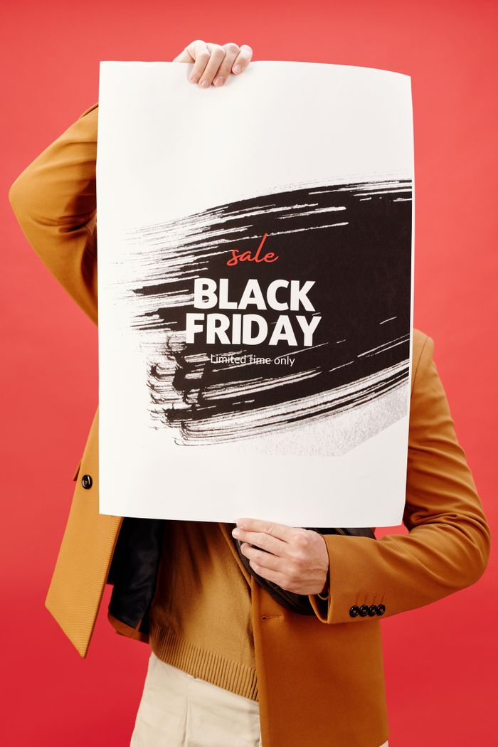 Individual holding a vibrant Black Friday sale poster against a red background.